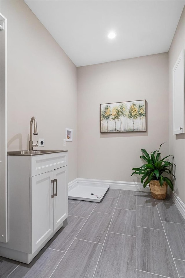 clothes washing area with cabinets, hookup for a washing machine, and sink