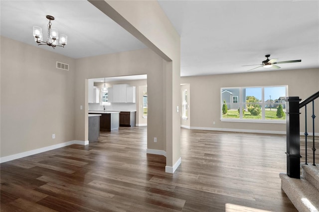 unfurnished living room with dark hardwood / wood-style floors, sink, and ceiling fan with notable chandelier