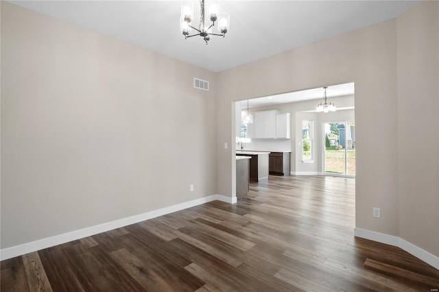 unfurnished living room with dark wood-type flooring and a notable chandelier