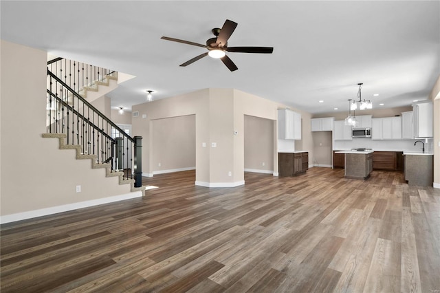 unfurnished living room with ceiling fan with notable chandelier, sink, and hardwood / wood-style floors