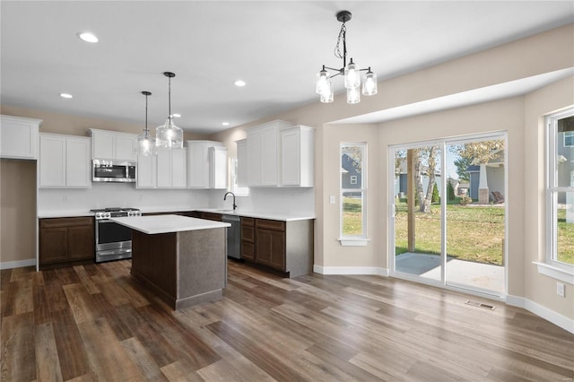 kitchen featuring dark wood-type flooring, stainless steel appliances, pendant lighting, and a center island