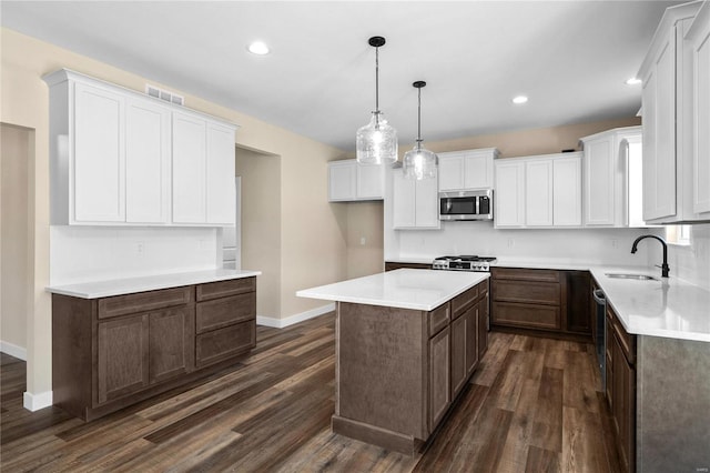 kitchen with white cabinets, a center island, dark hardwood / wood-style flooring, sink, and hanging light fixtures