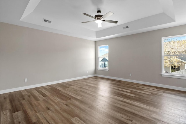 spare room with ceiling fan, hardwood / wood-style floors, and a tray ceiling