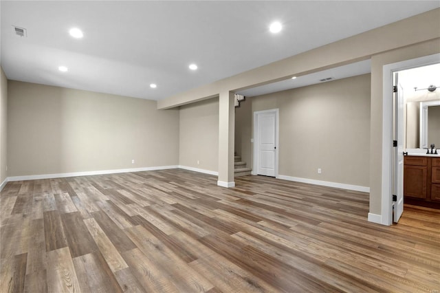 basement with sink and light hardwood / wood-style flooring