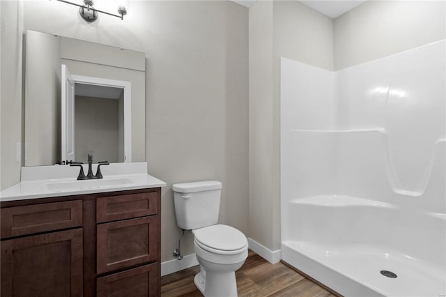 bathroom featuring toilet, a shower, hardwood / wood-style floors, and vanity