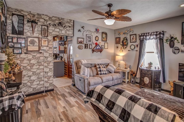 living room featuring ceiling fan, a textured ceiling, and light hardwood / wood-style floors