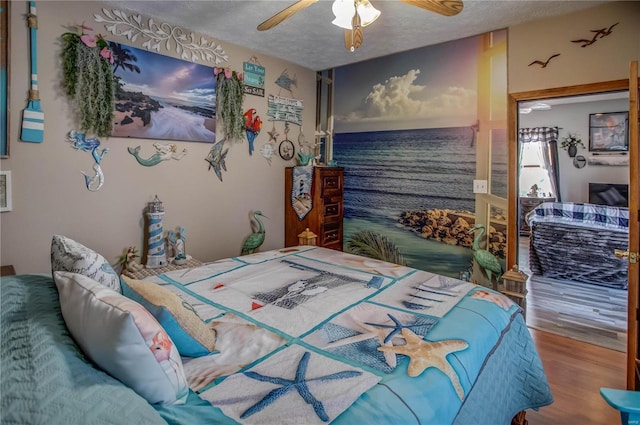 bedroom with ceiling fan, wood-type flooring, and a textured ceiling