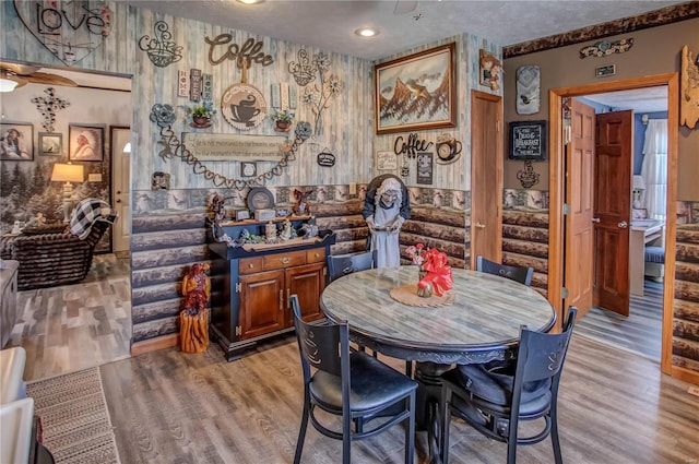 dining area with light hardwood / wood-style floors, a textured ceiling, and log walls