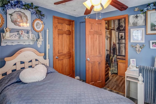 bedroom featuring a textured ceiling, ceiling fan, and dark hardwood / wood-style flooring