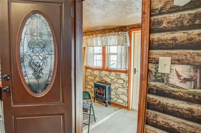 foyer with a wood stove, a textured ceiling, and light carpet