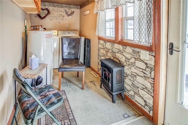 living area featuring water heater, a wood stove, carpet floors, and washer / clothes dryer