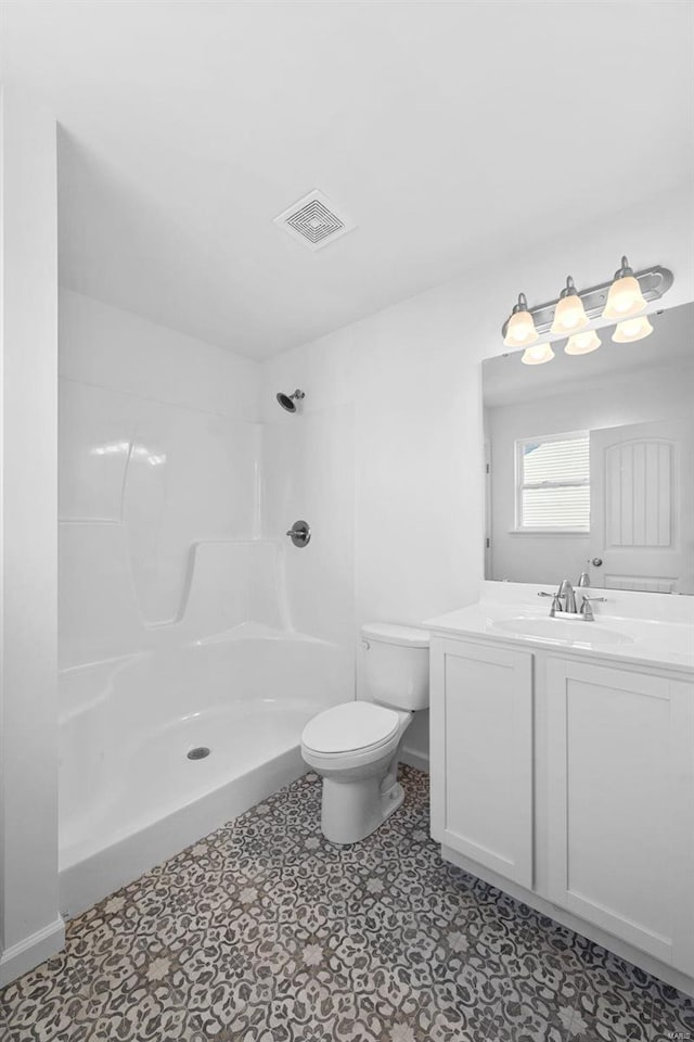 bathroom featuring toilet, vanity, and a shower