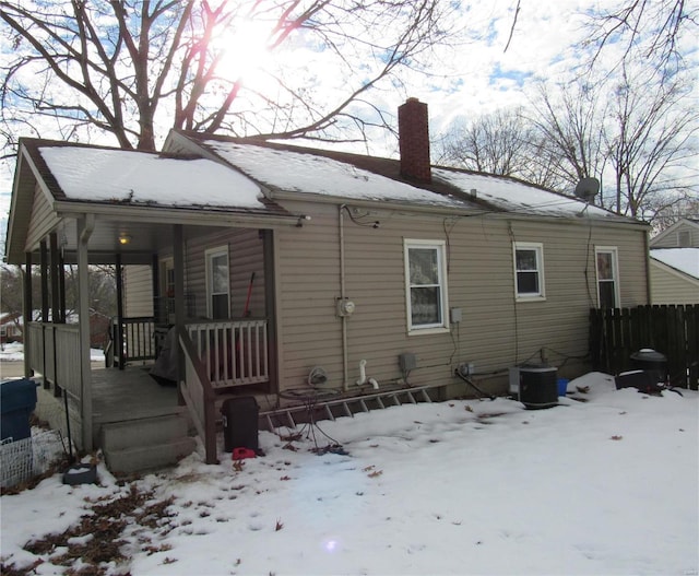 snow covered house featuring central AC and covered porch