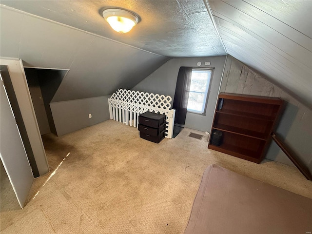 bonus room featuring lofted ceiling, light colored carpet, and a textured ceiling