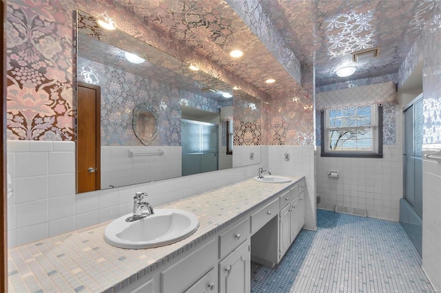 bathroom featuring bath / shower combo with glass door, tile walls, tile patterned floors, and vanity