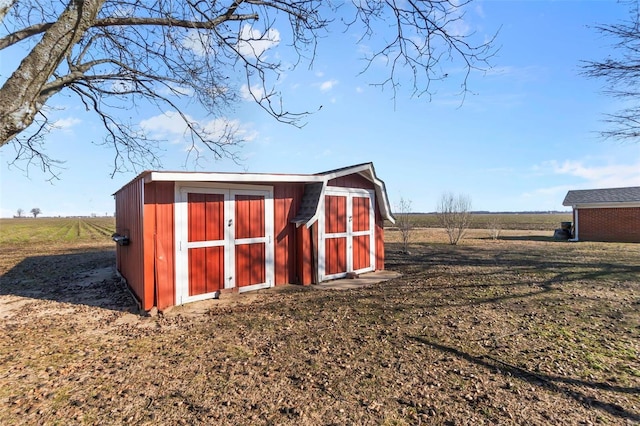 view of outbuilding featuring a rural view and a lawn