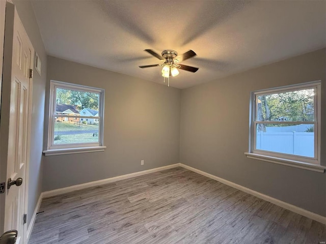 spare room featuring ceiling fan, a healthy amount of sunlight, a textured ceiling, and light hardwood / wood-style flooring