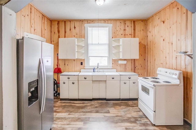 kitchen with white electric range, stainless steel fridge, wooden walls, white cabinets, and light wood-type flooring