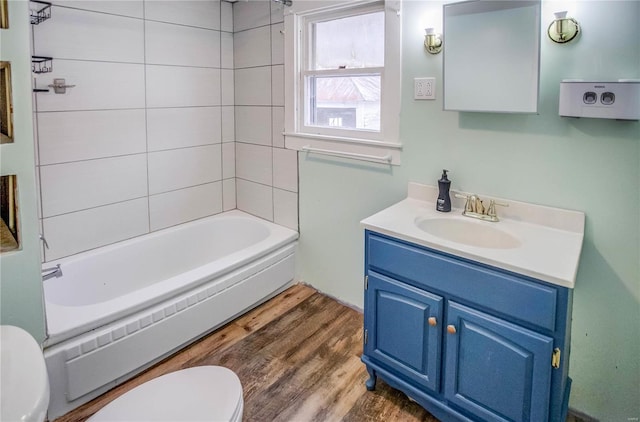 full bathroom featuring washtub / shower combination, wood-type flooring, toilet, and vanity