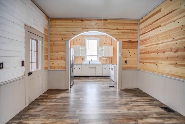 interior space featuring hardwood / wood-style flooring, wooden walls, and sink