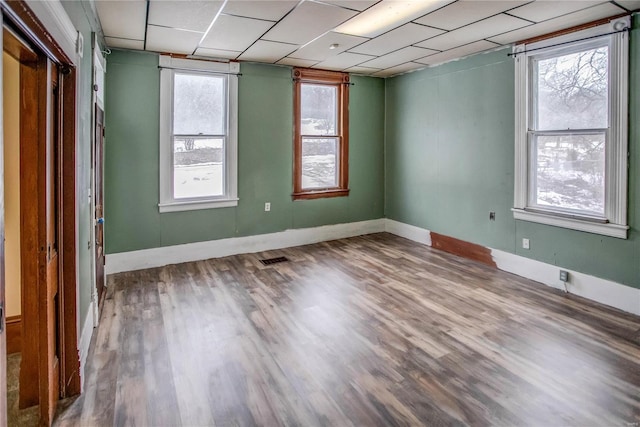 unfurnished room with hardwood / wood-style flooring and a paneled ceiling