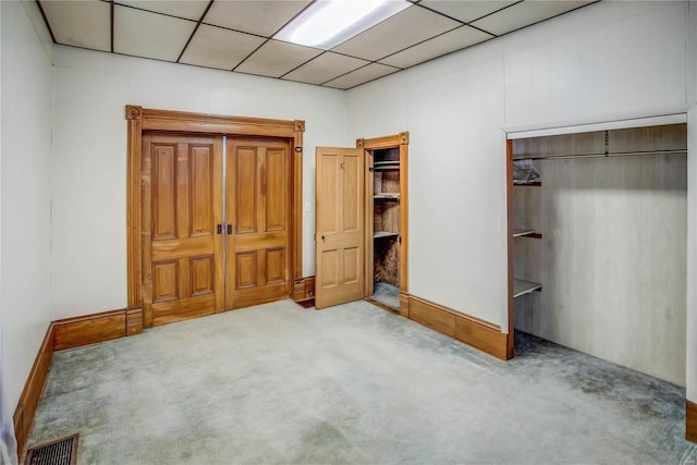 unfurnished bedroom featuring light colored carpet and a drop ceiling