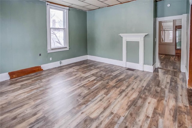 spare room featuring hardwood / wood-style flooring and a drop ceiling