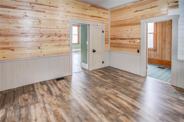 spare room with hardwood / wood-style floors and wood walls