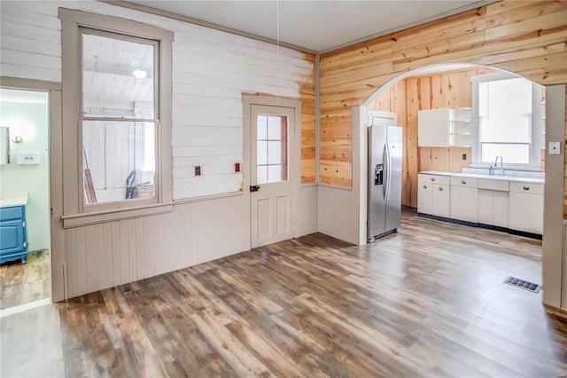 kitchen with white cabinets, stainless steel fridge, sink, and light wood-type flooring