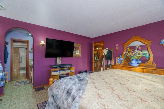 bedroom featuring a textured ceiling and connected bathroom