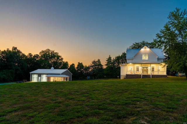 back house at dusk featuring a yard and a porch