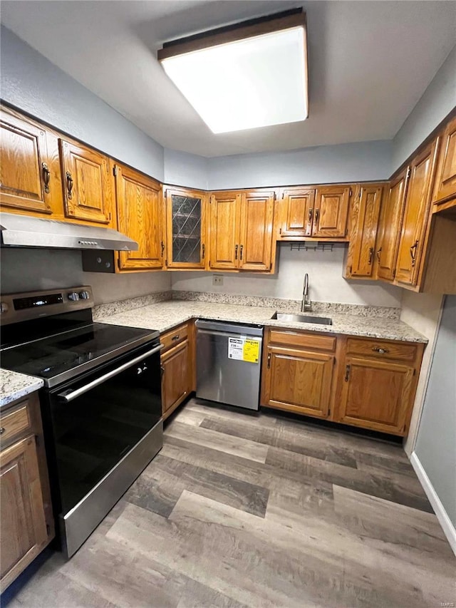 kitchen featuring dark hardwood / wood-style floors, electric range, dishwasher, light stone countertops, and sink