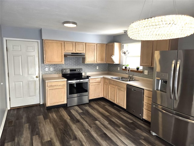 kitchen featuring sink, pendant lighting, appliances with stainless steel finishes, and an inviting chandelier