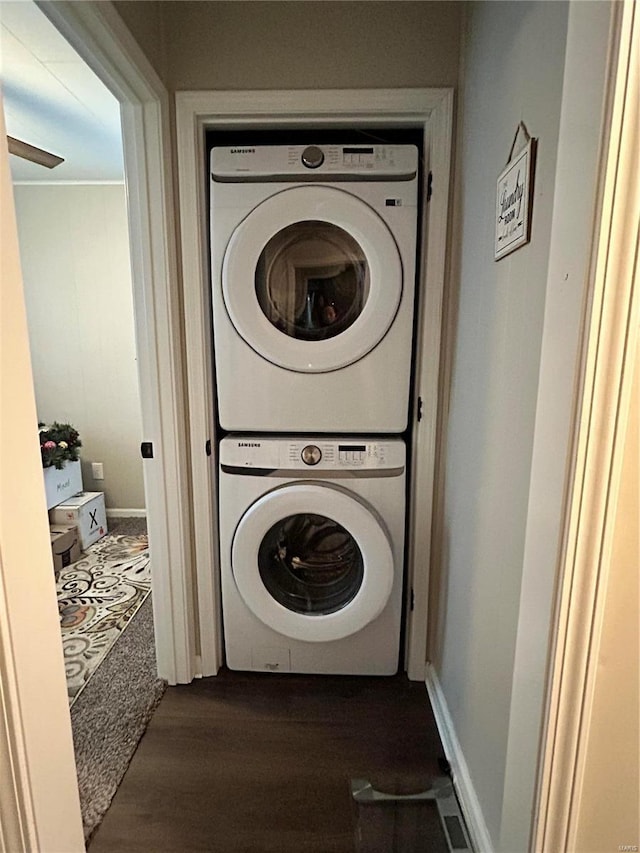 washroom featuring ceiling fan, dark wood-type flooring, and stacked washer and clothes dryer