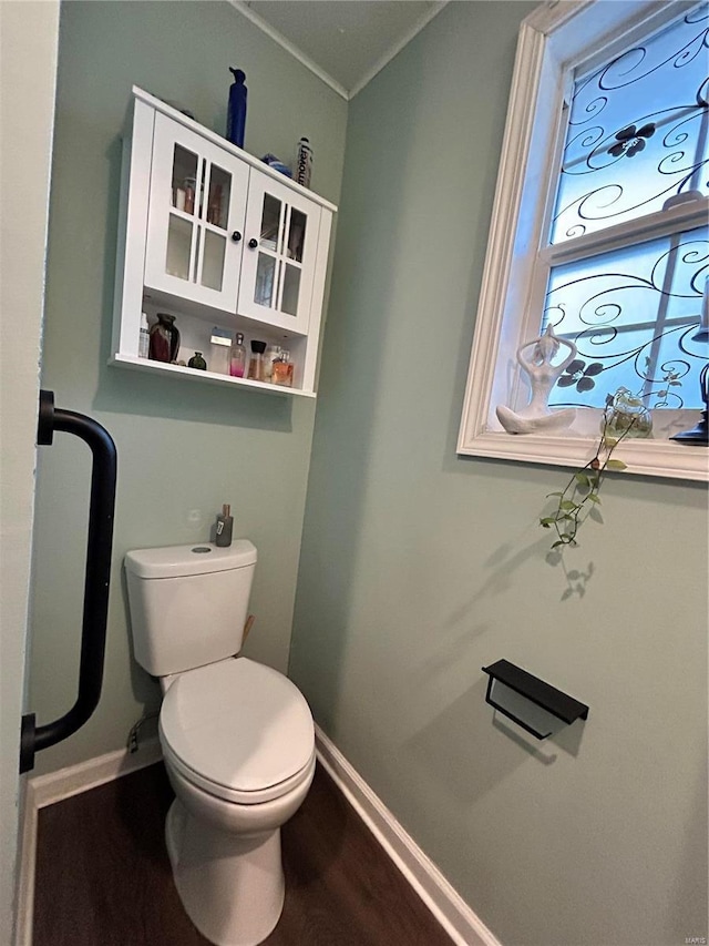 bathroom featuring toilet, ornamental molding, and wood-type flooring