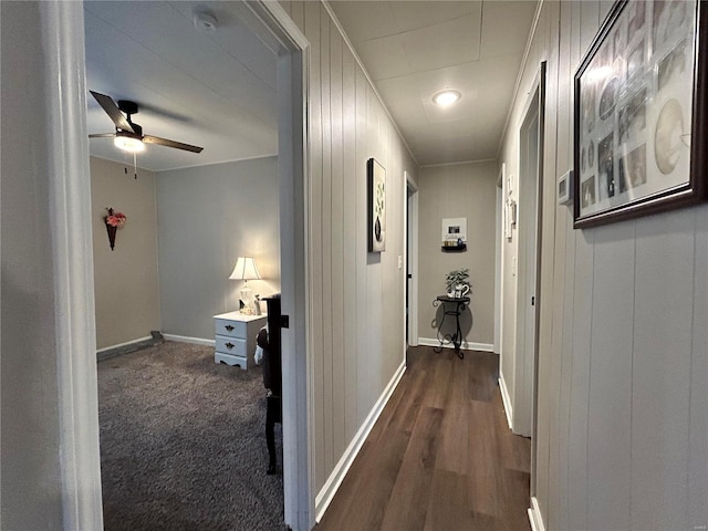 hallway featuring dark colored carpet and wooden walls