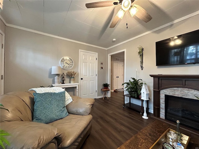 living room featuring dark wood-type flooring, crown molding, a stone fireplace, and ceiling fan