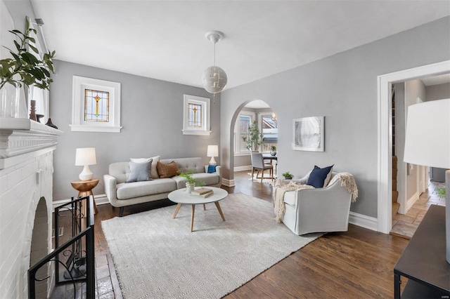 living room featuring a brick fireplace and dark wood-type flooring