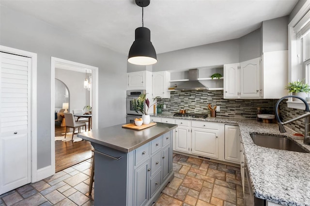 kitchen featuring sink, white cabinetry, a center island, and wall chimney exhaust hood