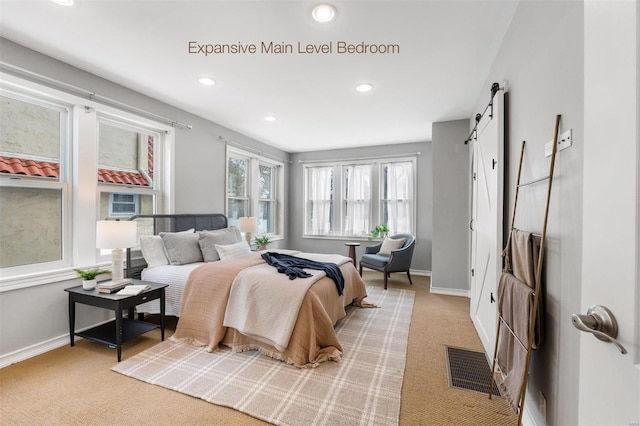 bedroom with a barn door and light colored carpet