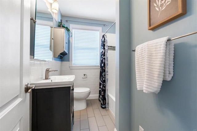 full bathroom featuring toilet, tile walls, plenty of natural light, and vanity