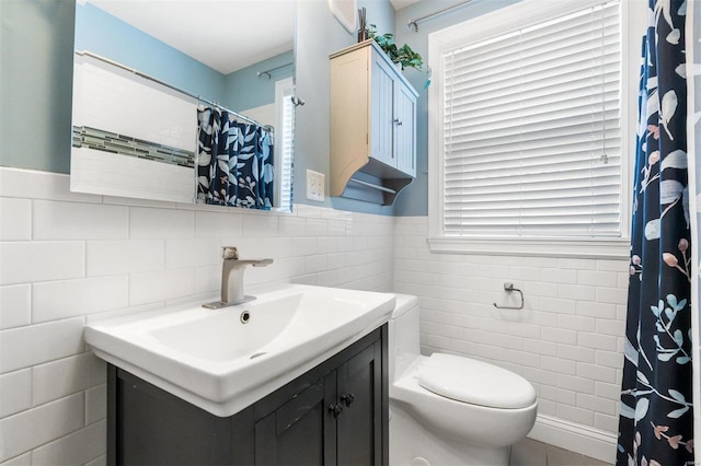 bathroom featuring toilet, tile walls, and vanity