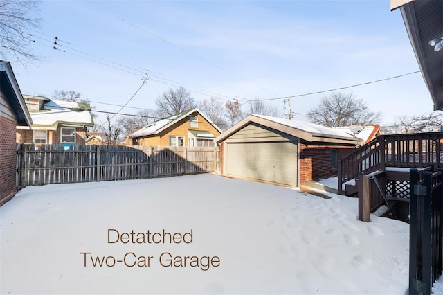 yard layered in snow featuring a deck, a garage, and an outbuilding