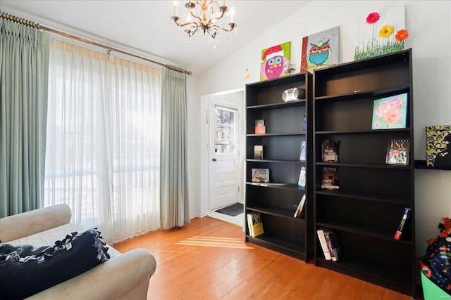 living area featuring hardwood / wood-style floors, a notable chandelier, and vaulted ceiling