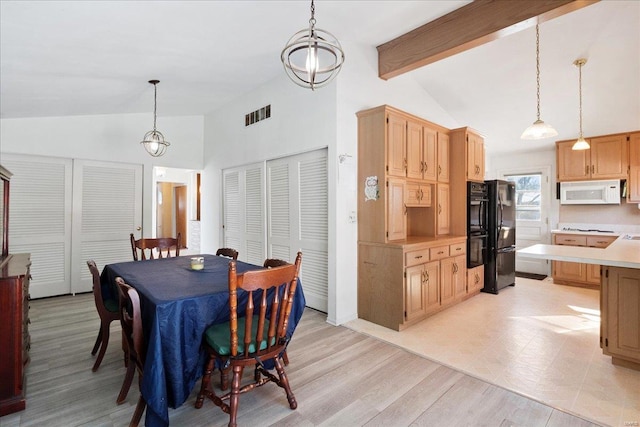 dining space featuring light hardwood / wood-style floors and vaulted ceiling with beams