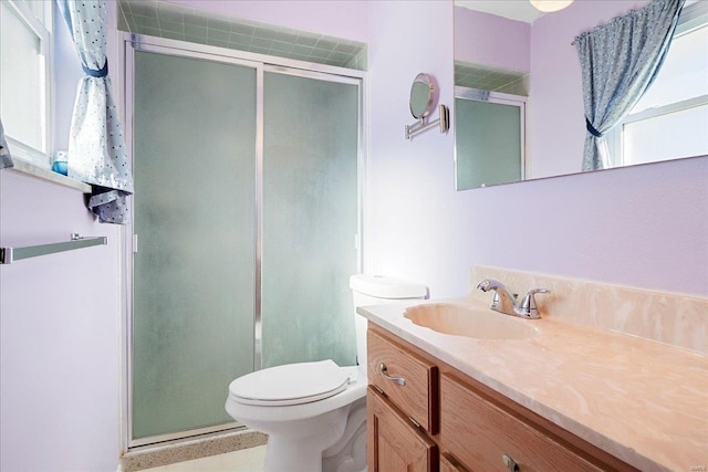 bathroom featuring toilet, a shower with shower door, and vanity