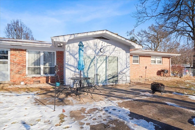 snow covered house featuring a fire pit and a patio