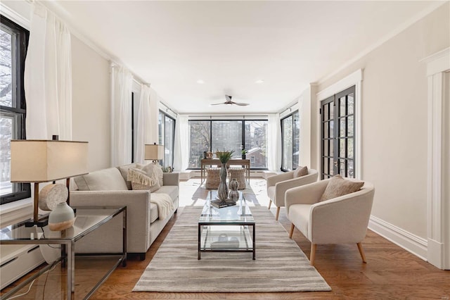 living room featuring ceiling fan, wood-type flooring, crown molding, and a healthy amount of sunlight