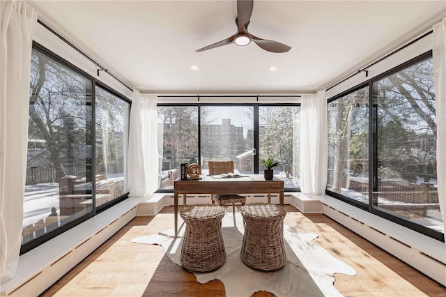 sunroom with ceiling fan and a baseboard heating unit