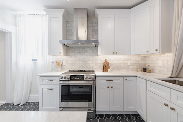 kitchen featuring backsplash, wall chimney range hood, stainless steel range with electric cooktop, and white cabinetry